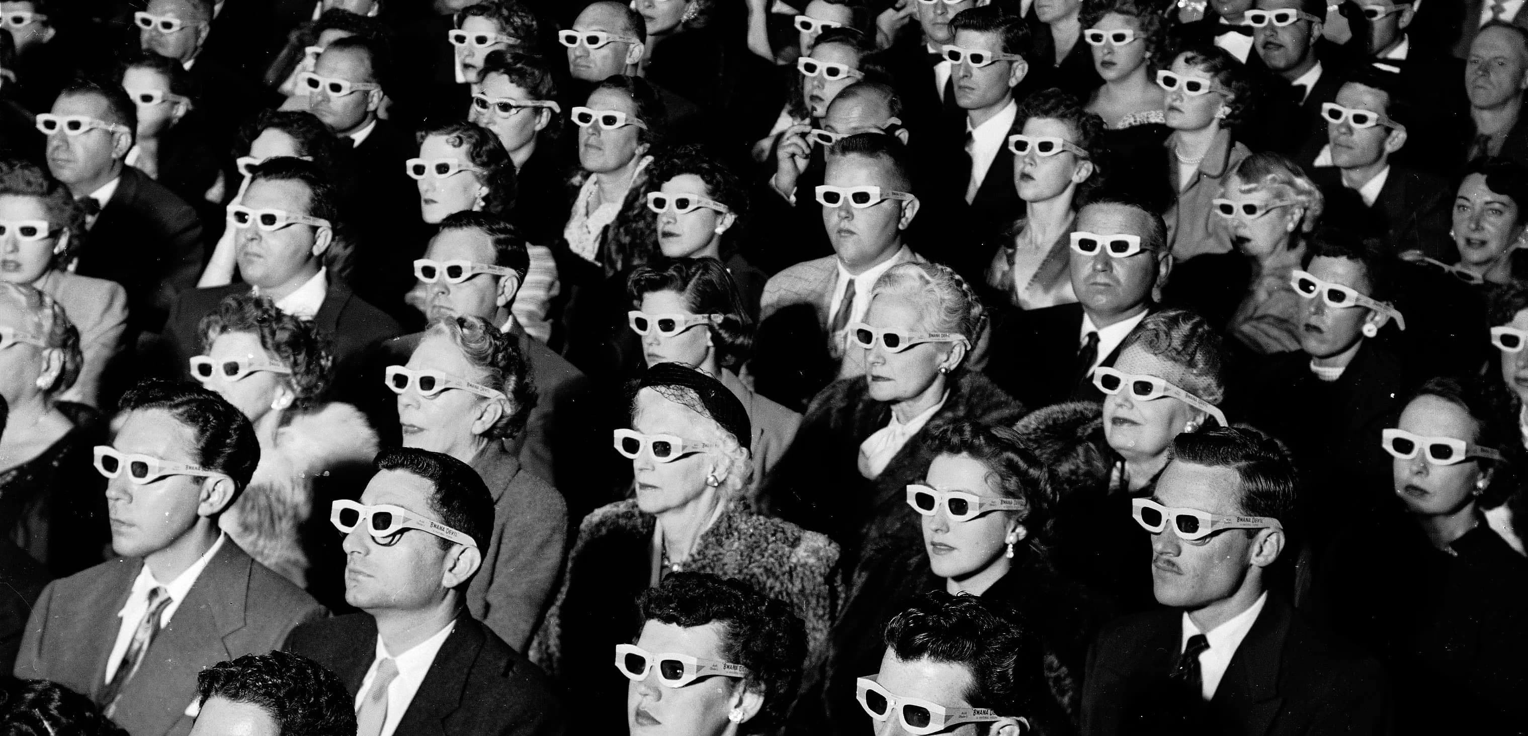 Público de un cine con gafas 3D, en blanco y negro.